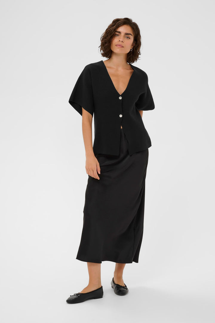 Femme portant le Cardigan Jessica noir avec coupe évasée et encolure en V, parfait pour un look minimaliste et élégant.