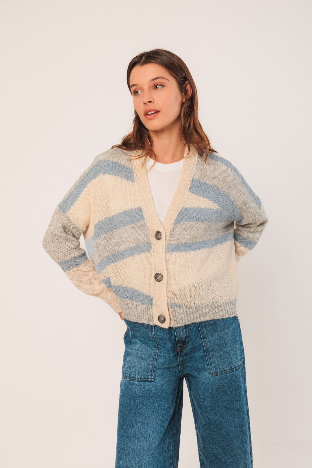 Cardigan en maille douce avec motifs graphiques, encolure en V et gros boutons, porté sur un jean.