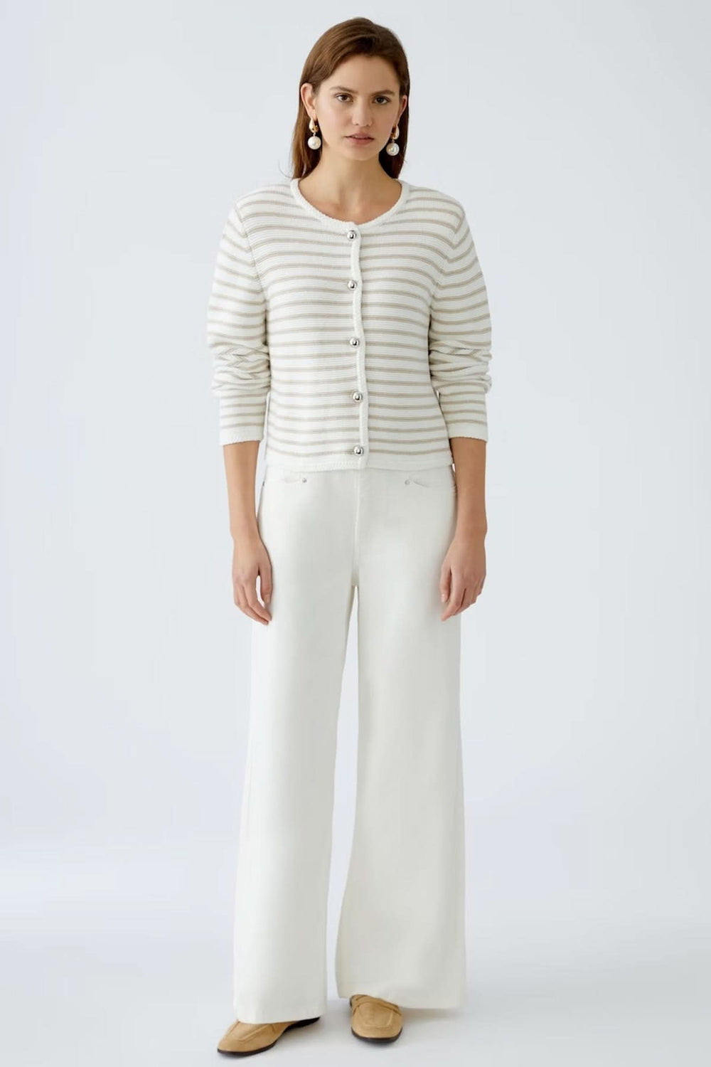 Cardigan à rayures moderne avec boutons contrastants, porté sur un débardeur, associé à un pantalon large blanc.