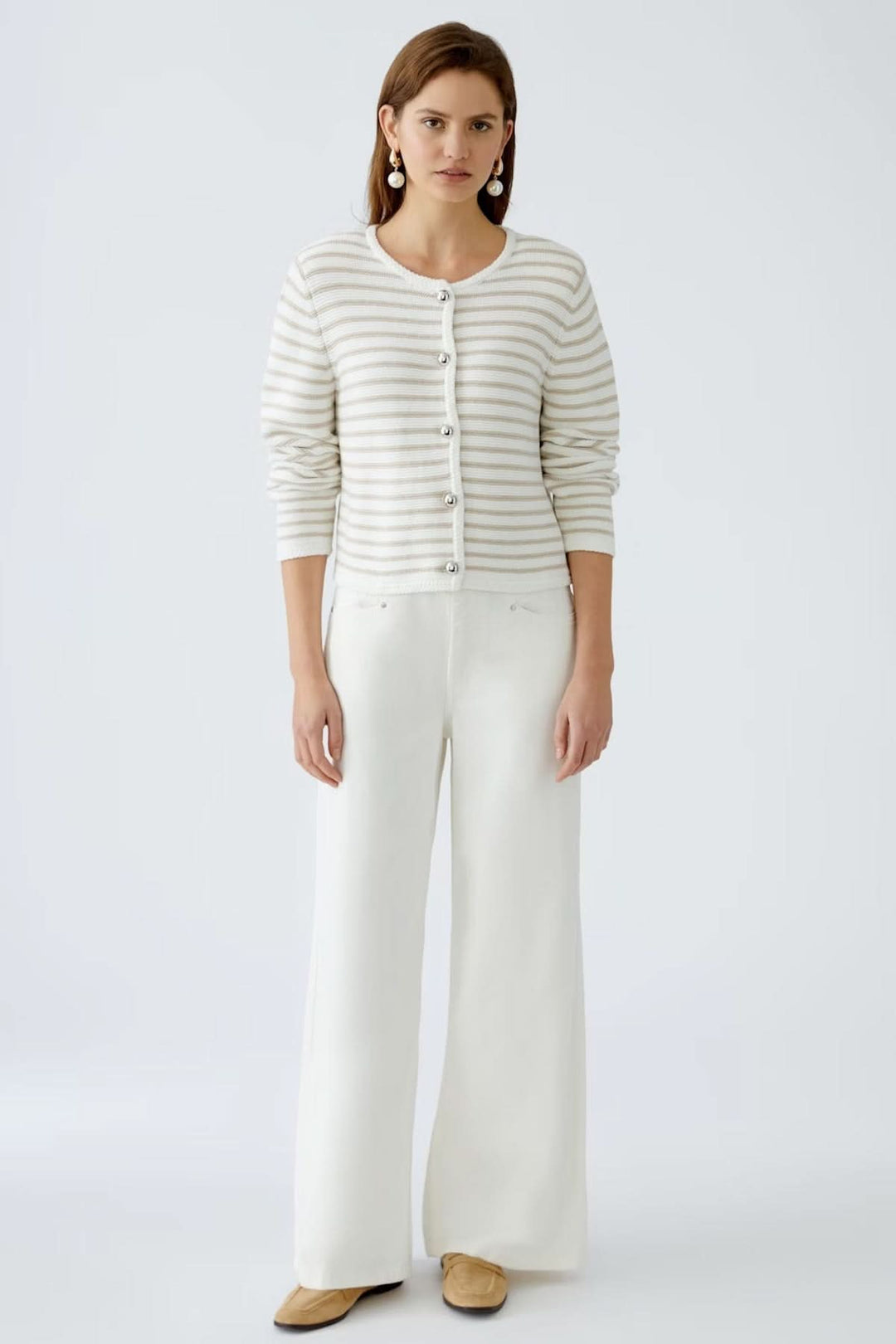 Cardigan à rayures moderne avec boutons contrastants, porté sur un débardeur, associé à un pantalon large blanc.