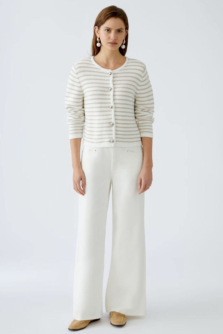 Cardigan à rayures moderne avec boutons contrastants, porté sur un débardeur, associé à un pantalon large blanc.