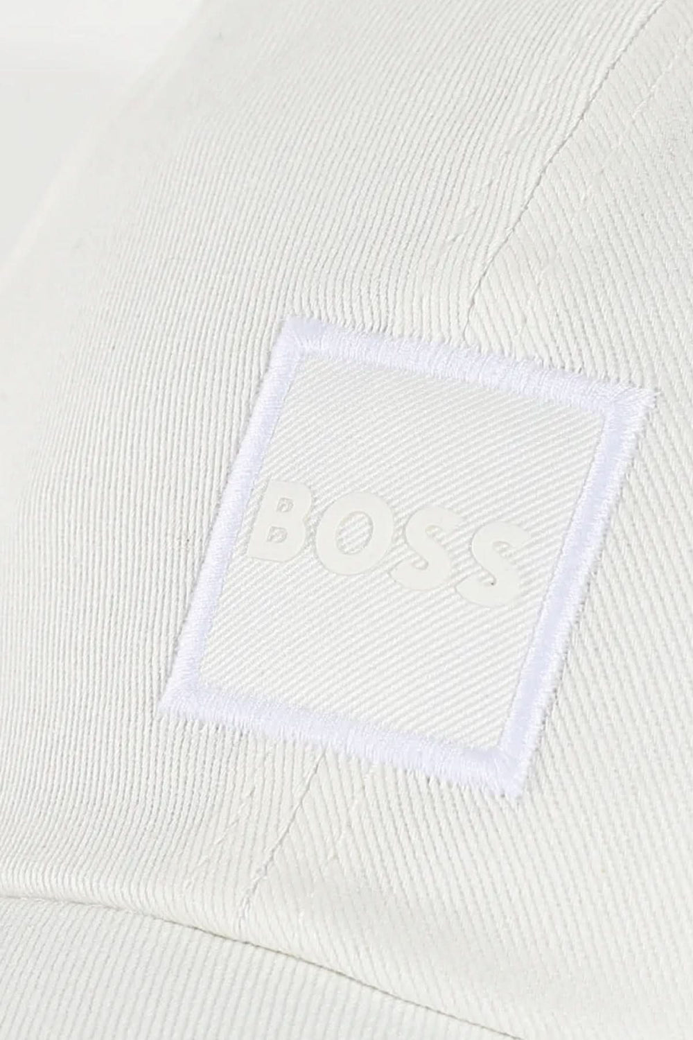 Écusson ton sur ton de la casquette BOSS sur tissu blanc, ajoutant une touche de style contemporain.