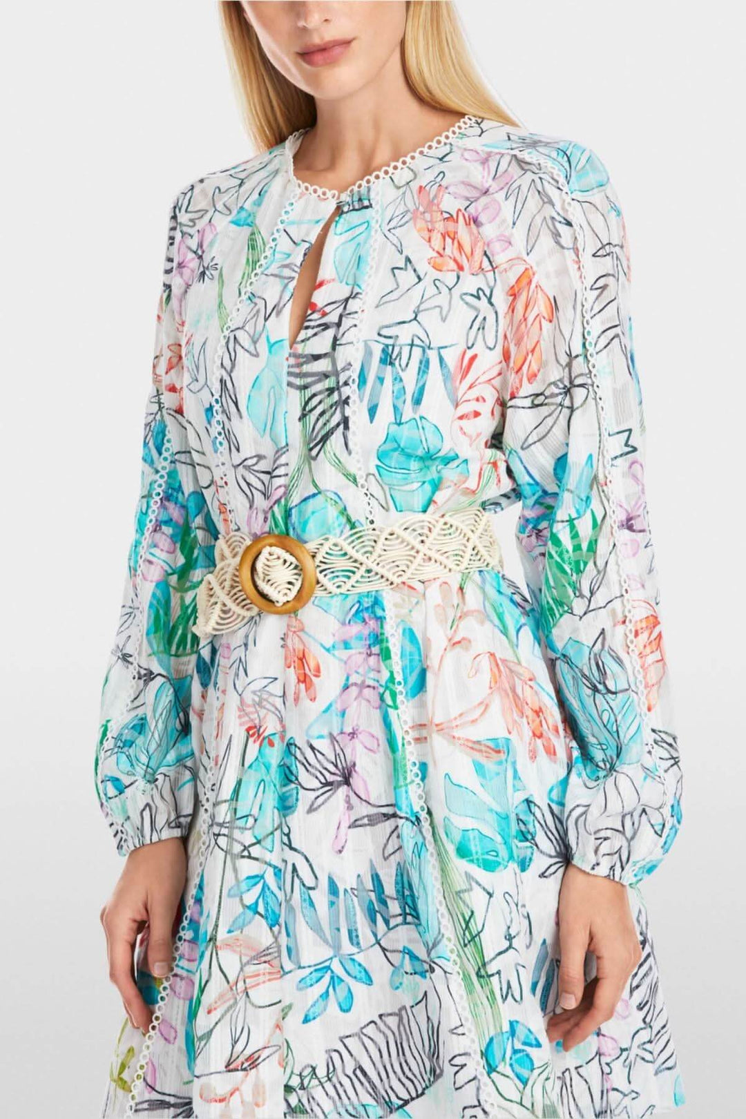 Ceinture de hanches en macramé avec boucle en bois portée sur une robe colorée à motifs floraux.