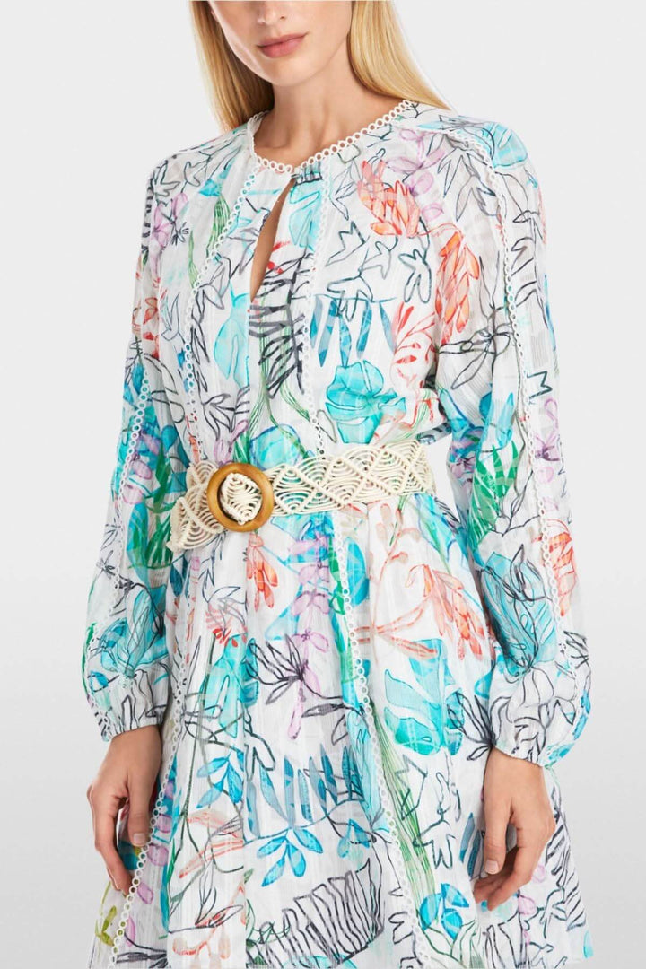 Ceinture de hanches en macramé avec boucle en bois portée sur une robe colorée à motifs floraux.