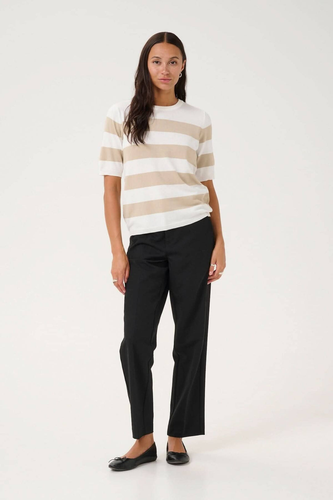 Femme portant un chandail à manches courtes rayé et un pantalon noir, look décontracté et élégant.