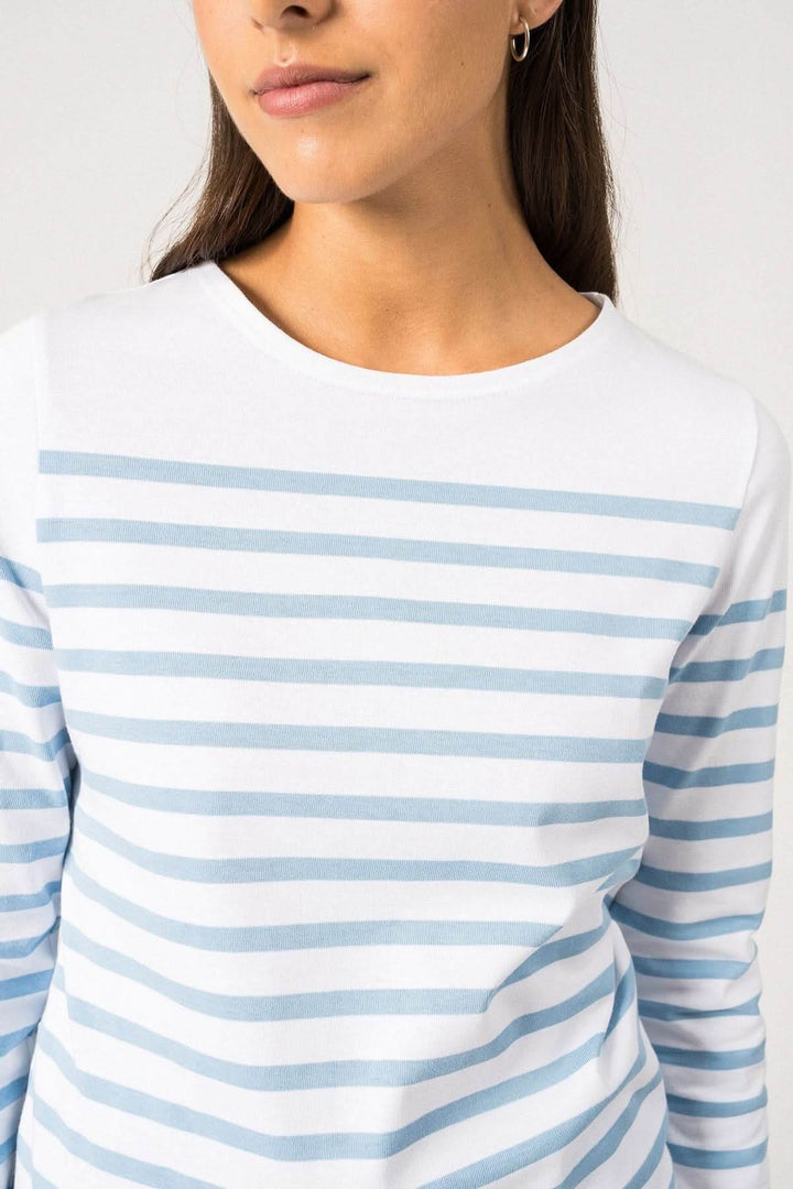 Femme portant un chandail naval en coton rayé bleu et blanc, avec une coupe ajustée et des manches longues.
