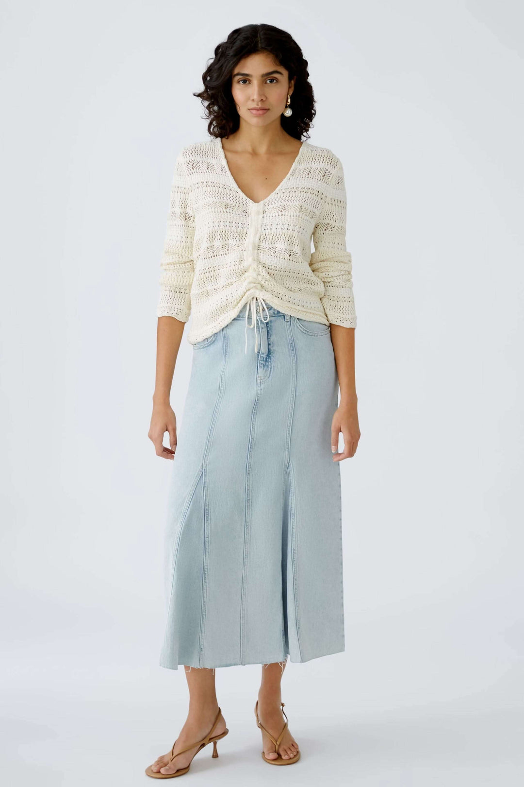 Chandail ajouré avec décolleté en V, porté avec une jupe longue en denim, pour une allure élégante et moderne.