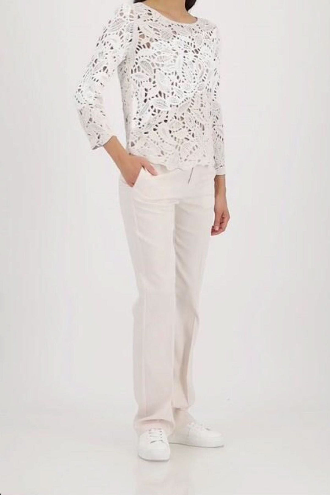 Chandail ajouré à motif géométrique en coton, élégant et moderne, porté avec un pantalon blanc, idéal pour superposer les textures.