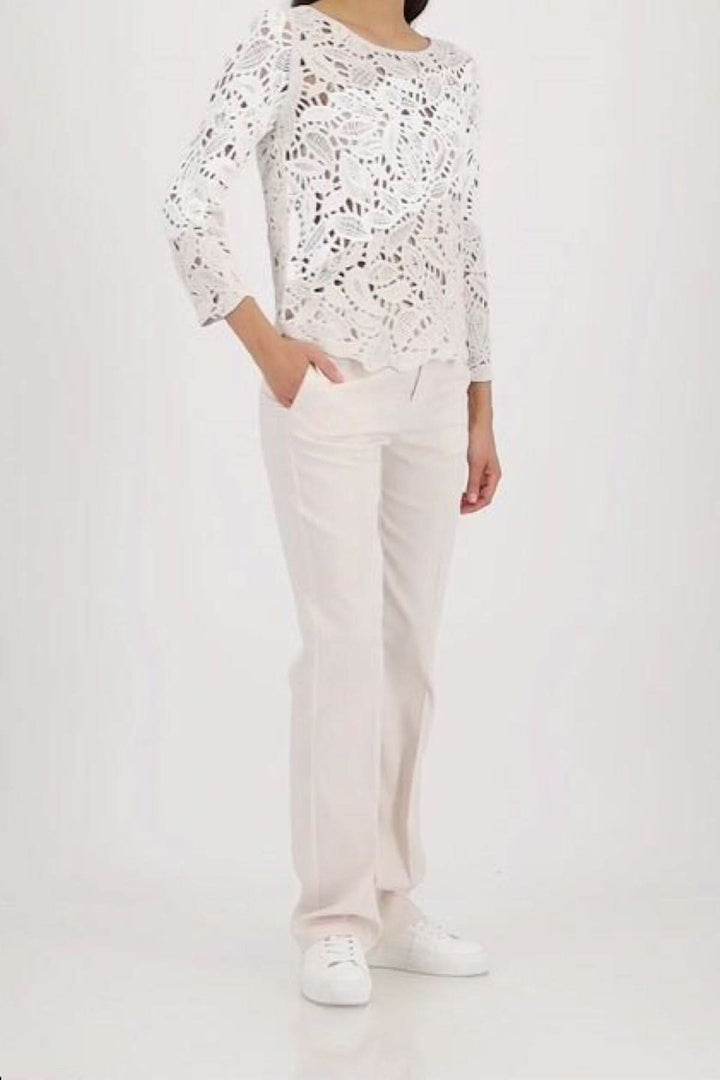 Chandail ajouré à motif géométrique en coton, élégant et moderne, porté avec un pantalon blanc, idéal pour superposer les textures.