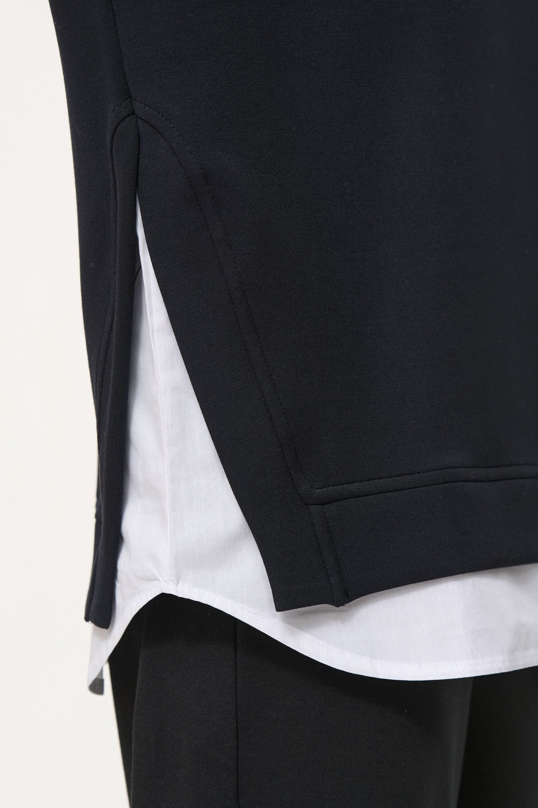 Chamail ample noir avec superposition de chemise blanche, détails oversize et ourlet arrondi.