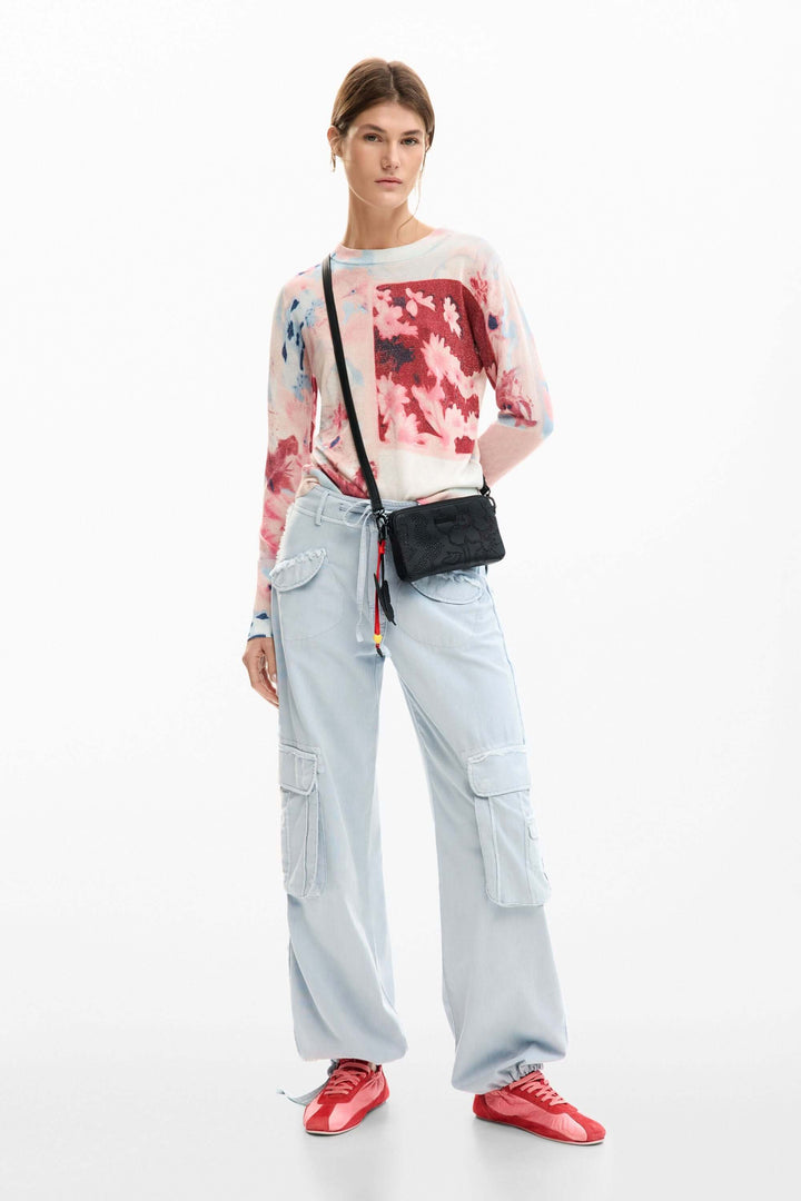 Femme portant un chandail avec collage artistique, tenue moderne et polyvalente avec pantalon clair et chaussures rouges. Mode contemporaine.