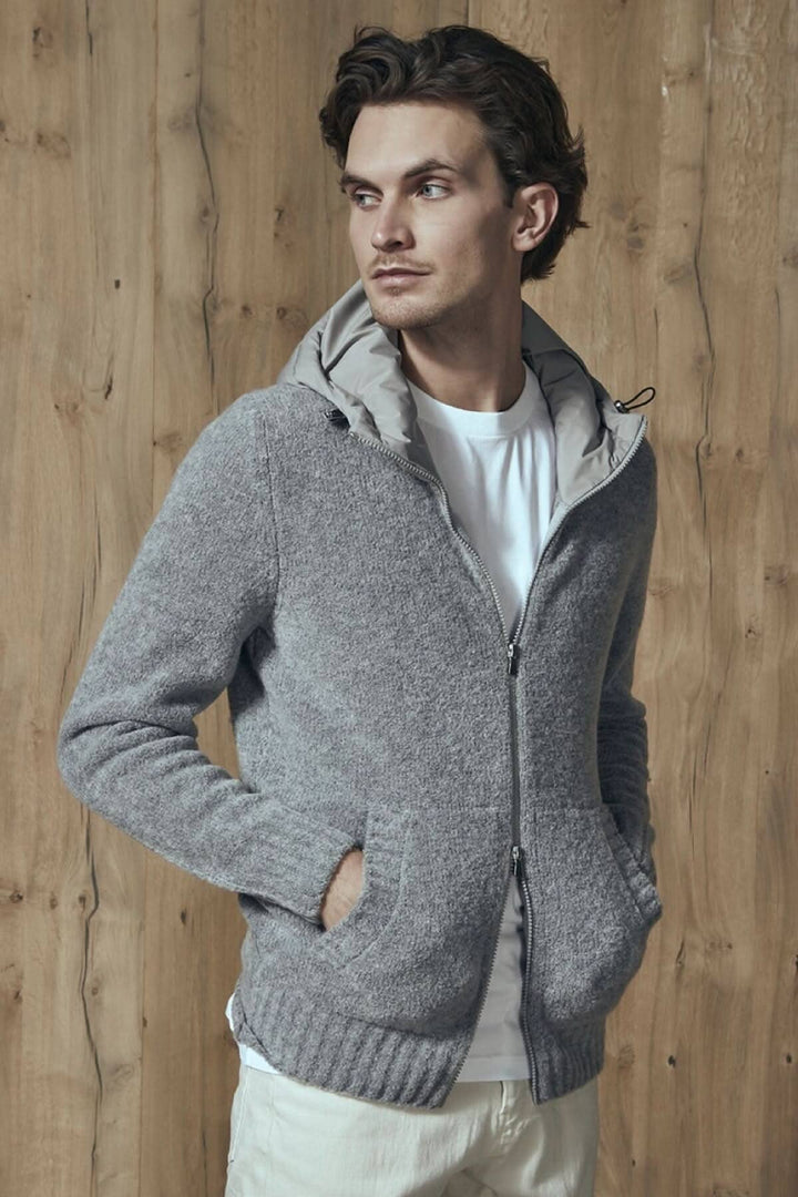 Homme portant un chandail à capuche en laine bouclée avec poches, sur fond en bois.