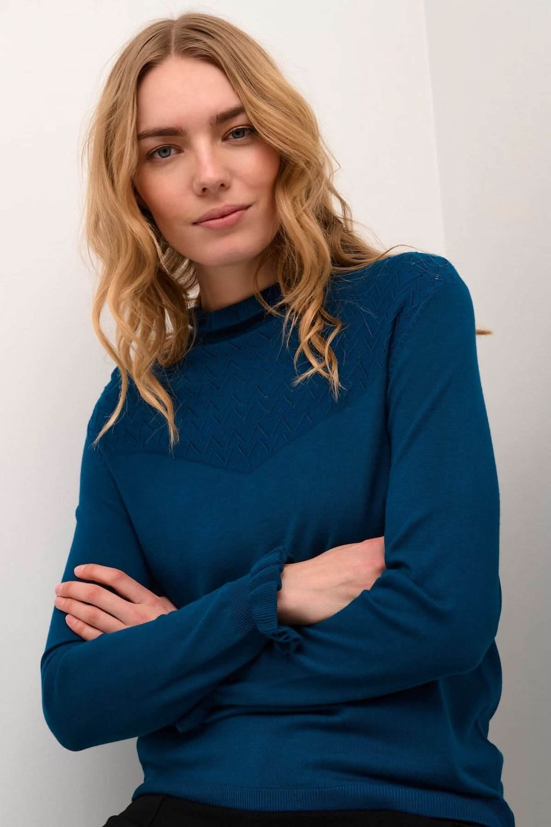 Femme portant un chandail à col montant avec détails ajourés aux épaules, coupe fluide et maille douce pour un style chic.