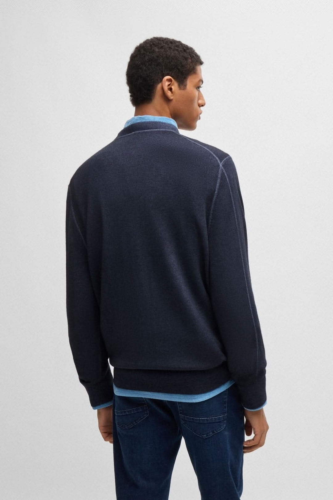 Homme portant un chandail col rond en laine navy, vu de dos, stylé avec une chemise sous-jacente.