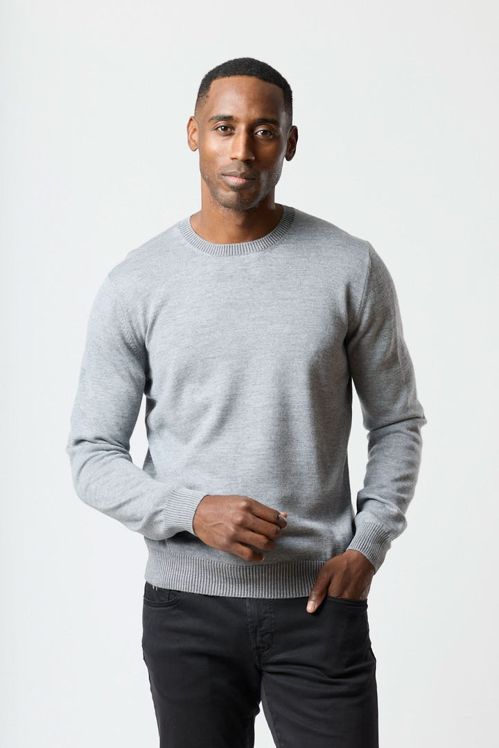 Homme portant un chandail col rond essentiel gris, coupe régulière et finitions côtelées, offrant confort quotidien et style moderne.