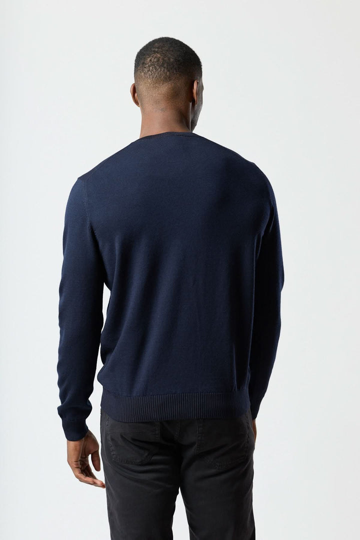 Homme portant un chandail col rond essentiel bleu marine avec finitions côtelées pour une silhouette moderne et élégante.