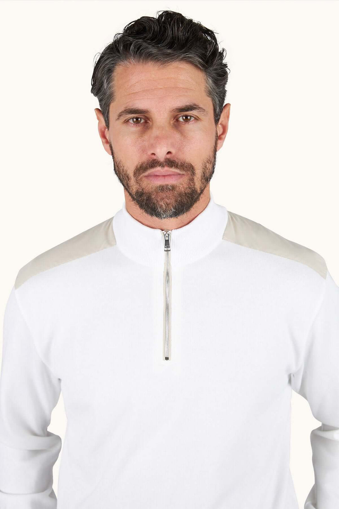 Homme portant un chandail à demi-zip blanc avec fermeture éclair, style moderne et décontracté chic, idéal pour superposition.