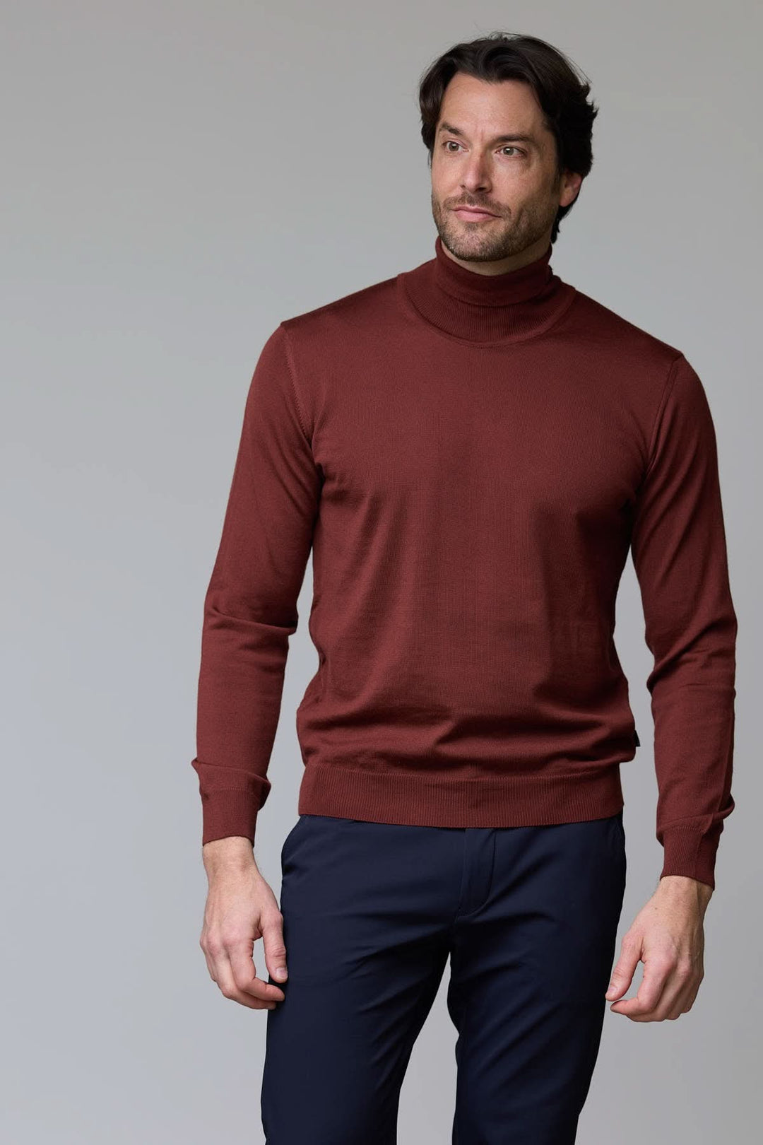 Homme portant un chandail en laine mérinos fine col rond marron avec pantalon bleu, style élégant et intemporel.