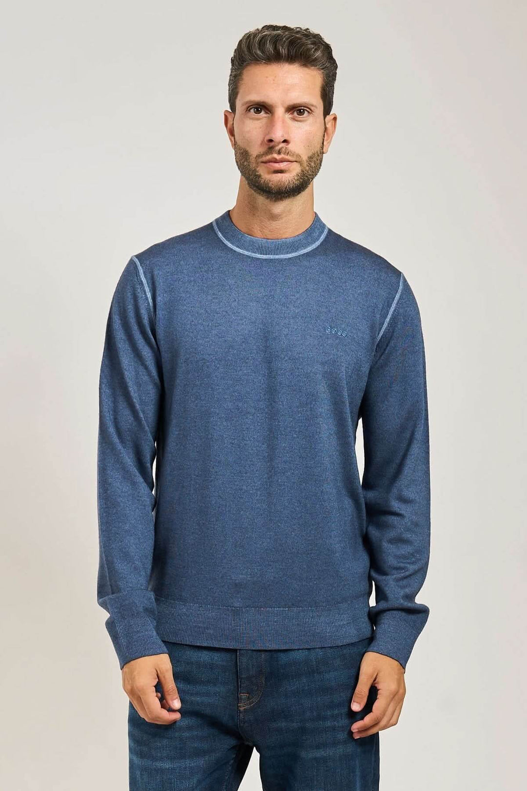 Homme portant un chandail en laine vierge à col rond BOSS Orange, manches longues, détails côtelés, élégant et confortable.