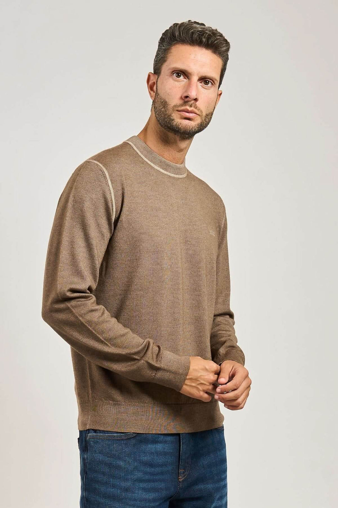 Homme portant un chandail en laine vierge à col rond avec manches longues et finitions côtelées, collection BOSS Orange, couleur marron.