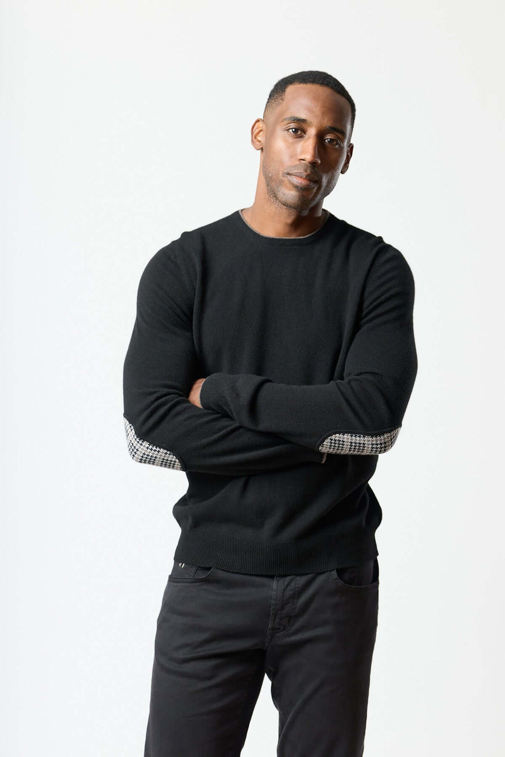 Homme portant un chandail en laine vierge et cachemire avec coudières pied-de-poule, reflet de l'élégance italienne et du confort.