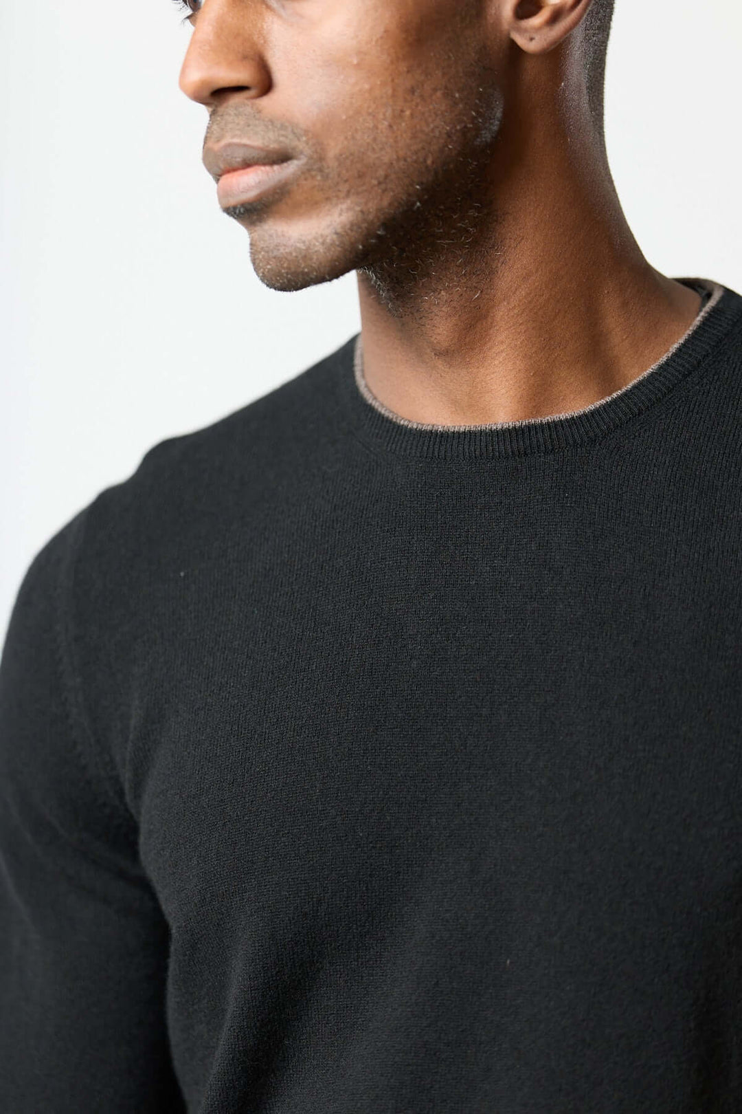Homme portant un chandail en laine vierge et cachemire noir avec coudières pied-de-poule, élégance Gran Sasso.