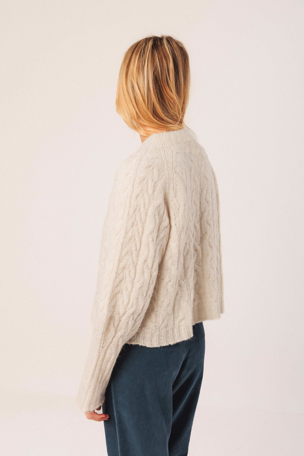 Chandail en maille torsadée beige, au design ample et col rond, parfait pour une tenue décontractée élégante.