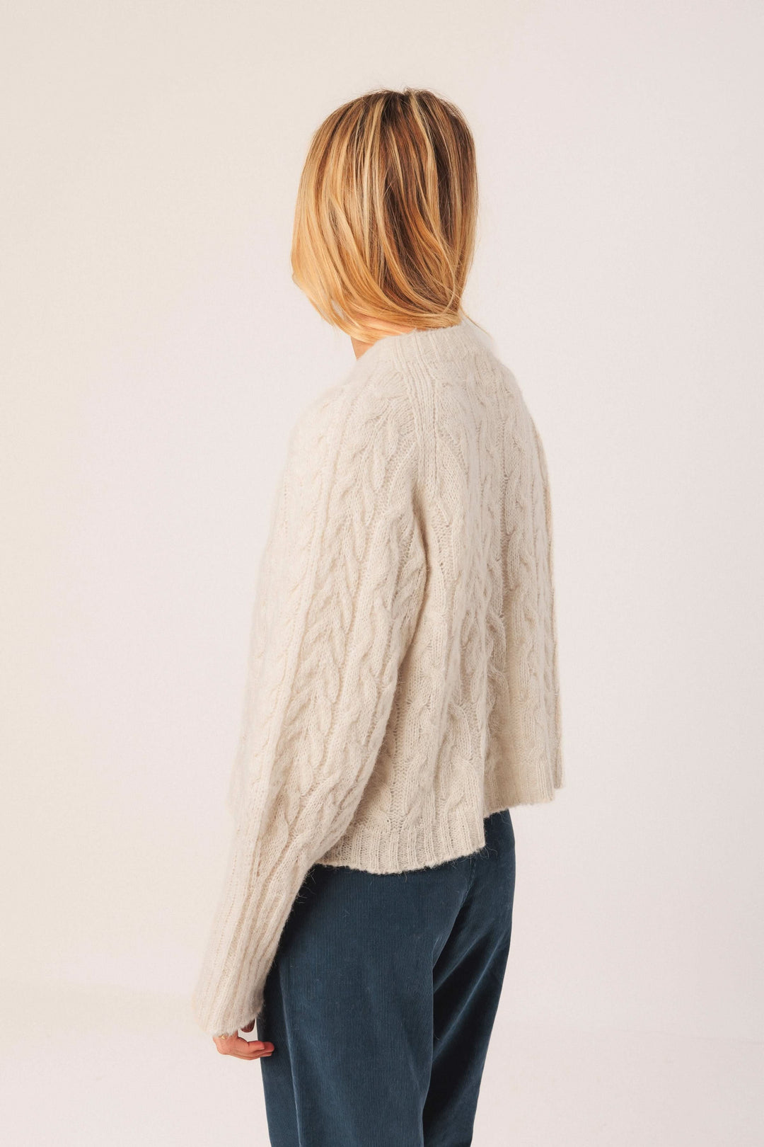 Chandail en maille torsadée beige, au design ample et col rond, parfait pour une tenue décontractée élégante.