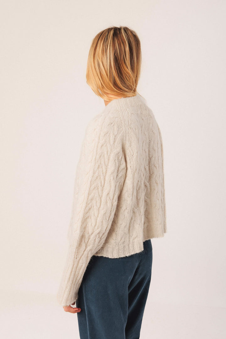 Chandail en maille torsadée beige, au design ample et col rond, parfait pour une tenue décontractée élégante.