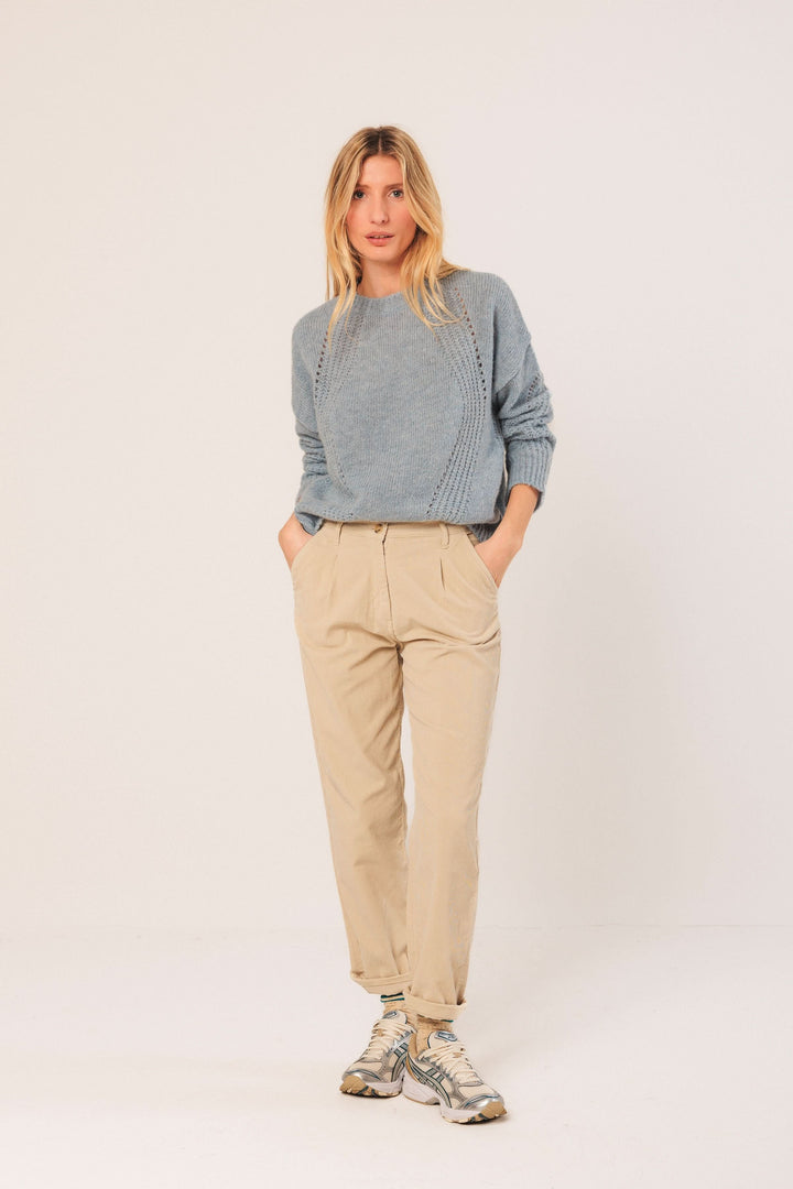 Chandail en maille légère bleu avec détails ajourés, pantalon beige, look décontracté moderne.