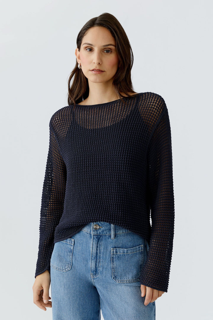 Femme portant un chandail en maille ajourée à manches longues, parfait pour un look moderne et superposé.