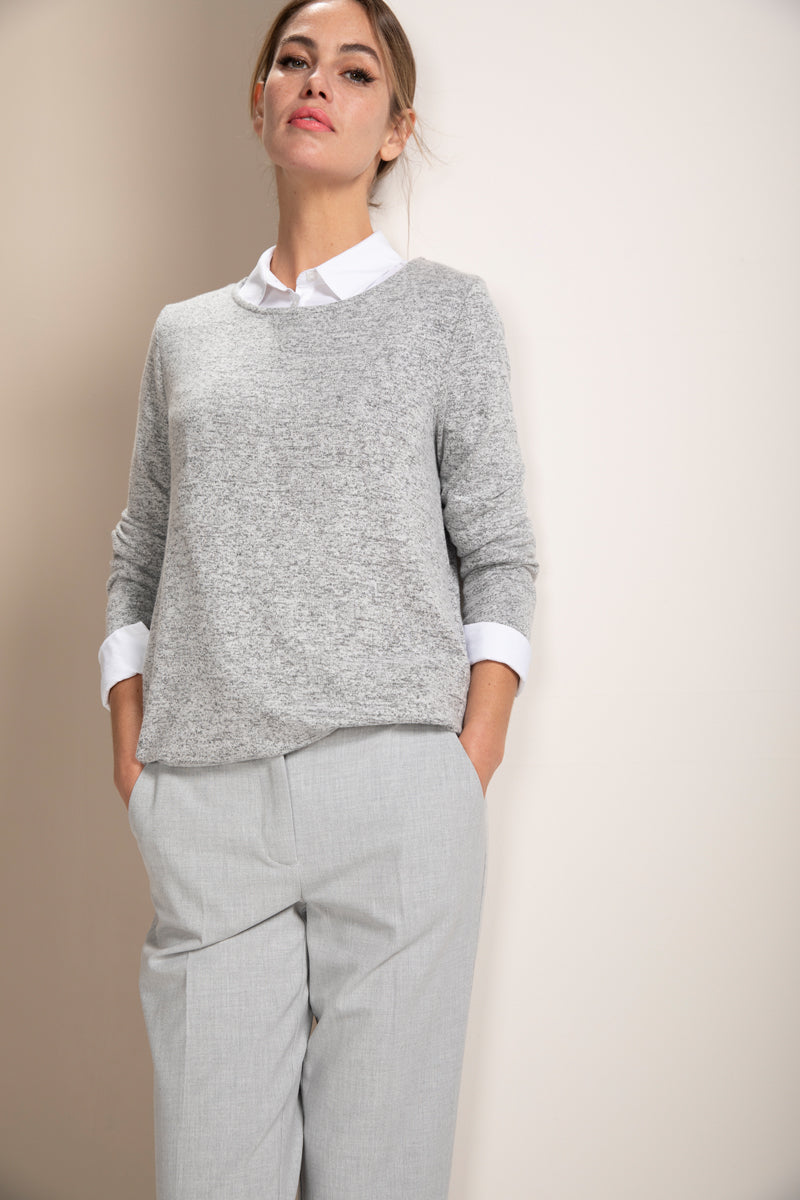 Femme portant un chandail en maille douce gris avec un pantalon décontracté, élégance et confort modernes.