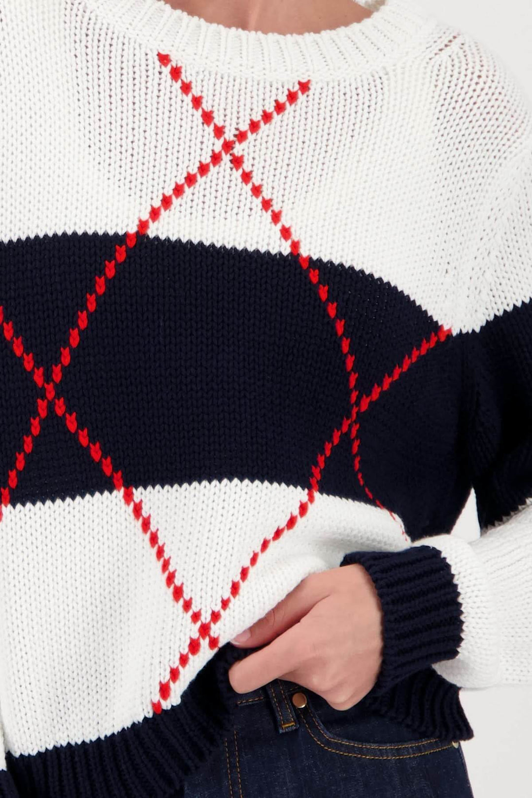 Chandail en maille à motif géométrique sur fond blanc avec lignes rouges et bleues, coupe droite, encolure arrondie, style moderne.