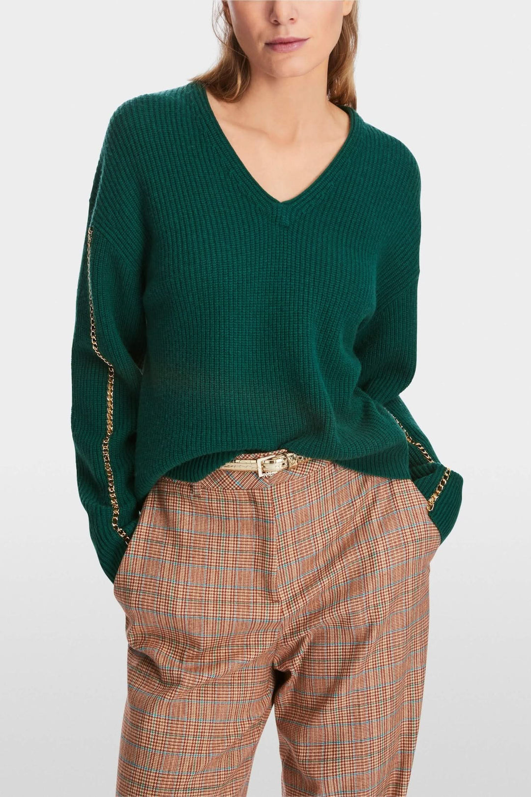 Pull en maille verte à col en V avec chaîne dorée, coupe large et décontractée.