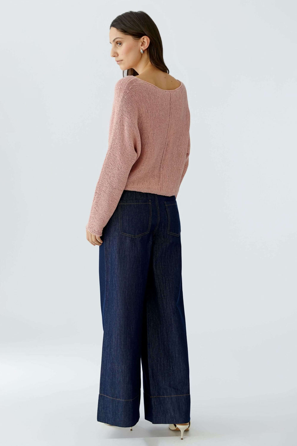 Vue arrière d'un chandail en ruban tricoté rose avec encolure dégagée, porté avec un pantalon en jean évasé.