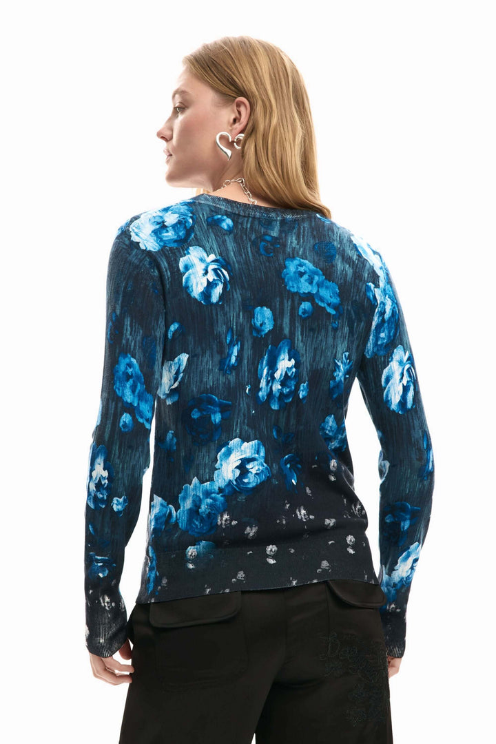 Femme portant un chandail fin à fleurs bleu, coupe ajustée et manches longues, vue arrière.