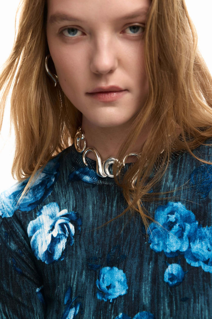 Femme portant un chandail fin à fleurs bleu avec une coupe ajustée et un style moderne, idéal pour l&