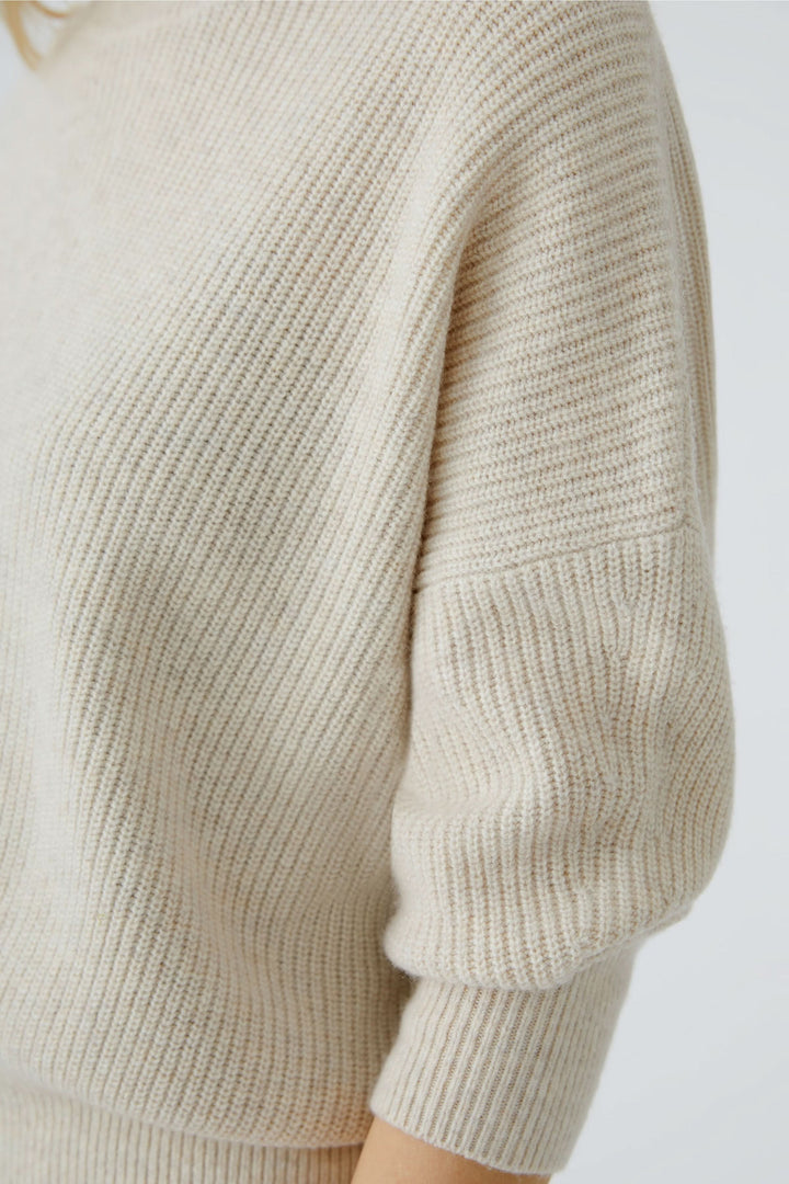 Chandail en maille fine beige à col montant, légèrement ample et manches courtes, parfait pour un look chic.