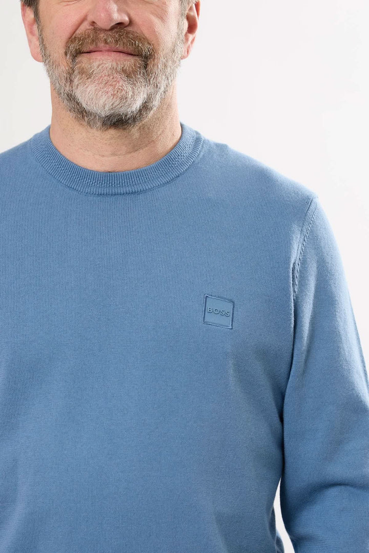 Homme portant un chandail à manches longues Hugo Boss bleu avec un logo discret sur le poitrine.