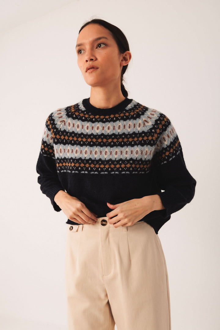 Chandail jacquard à col rond, style intemporel, porté avec un pantalon classique pour un look élégant.