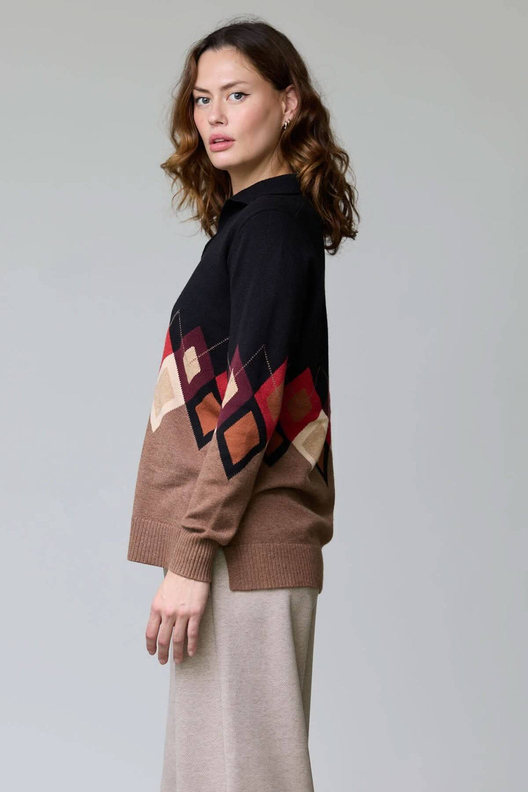 Femme portant un chandail à motif losanges avec col ouvert et manches multicolores, élégant et confortable pour la saison fraîche.