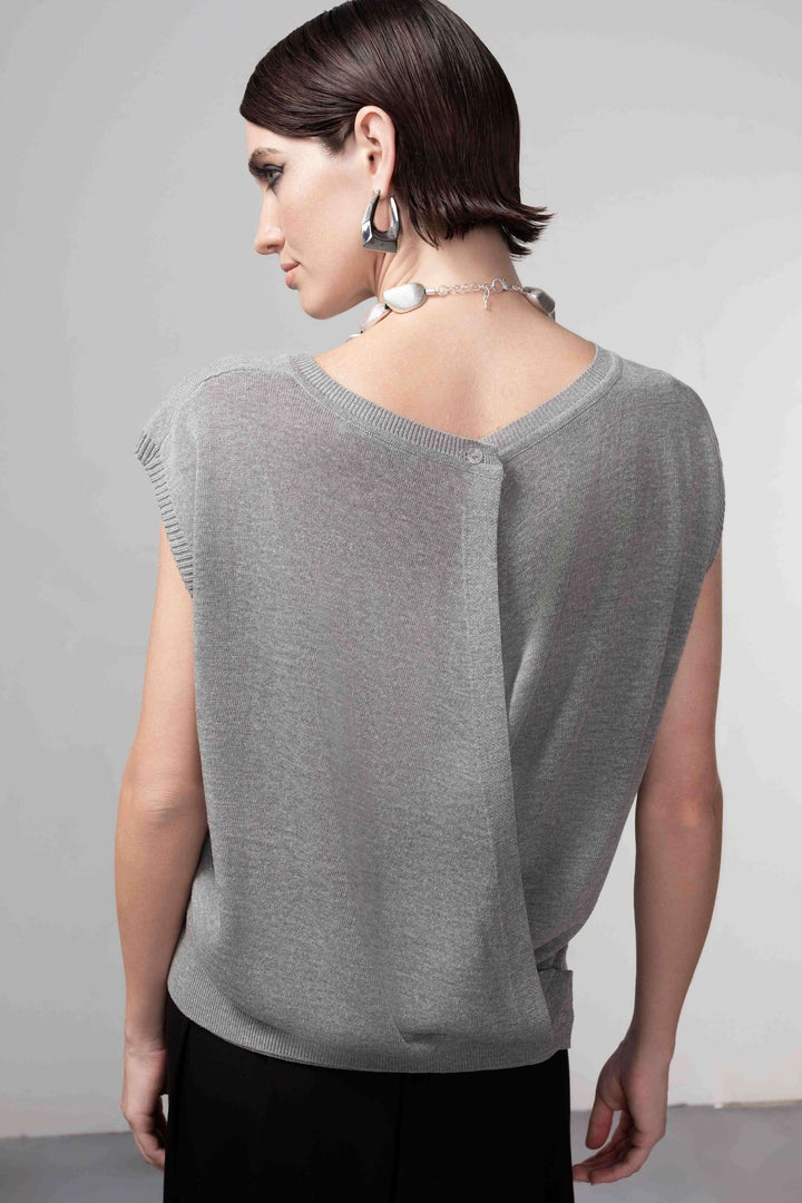 Femme portant un chandail sans manches avec ouverture au dos, coupe droite et maille fine. Chandail ouverture au dos chic et raffiné.