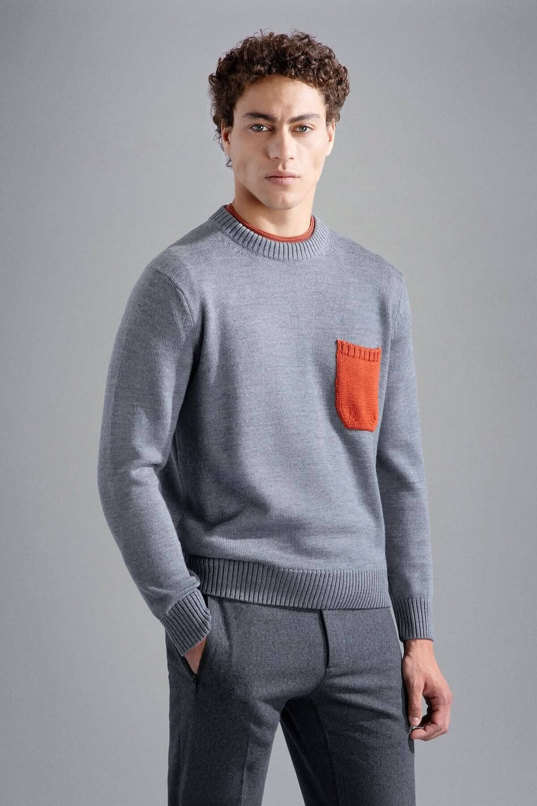 Pull gris clair avec poche orange, style décontracté et moderne, col rond et bords-côtes.