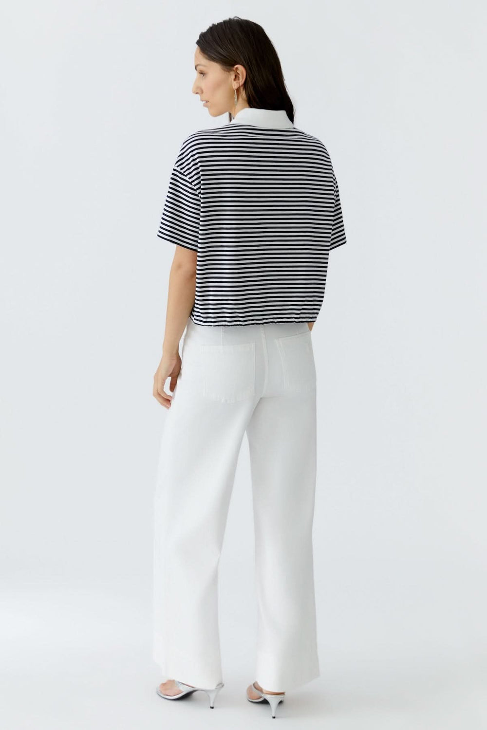 Femme portant un chandail polo à rayures avec cordon, vu de dos, style décontracté chic, coupe fluide, idéal pour un look quotidien.