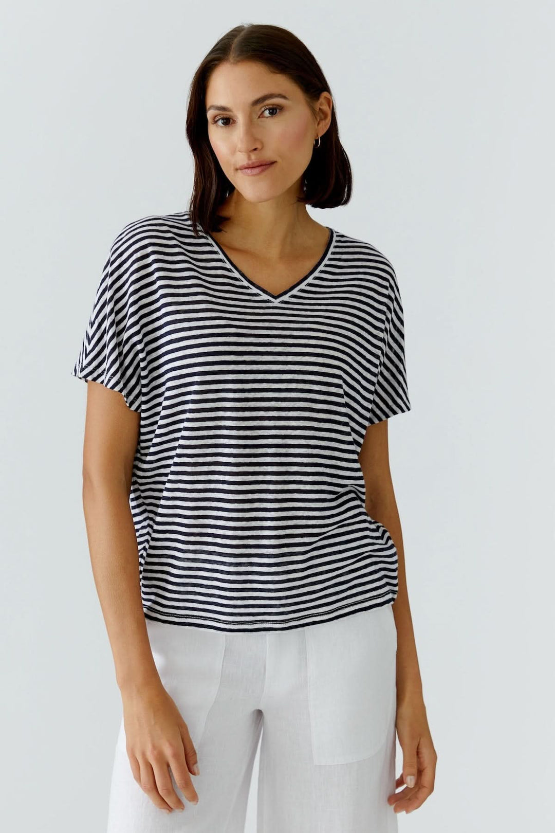 Femme portant un chandail à rayures col en v, coupe décontractée, manches courtes, style moderne et féminin.