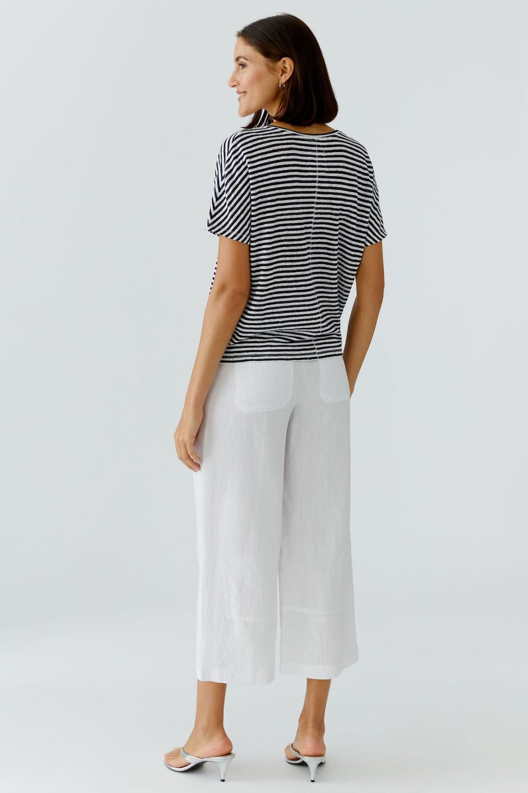 Femme portant un chandail à rayures col en v avec pantalon blanc, style décontracté élégant idéal pour le quotidien.