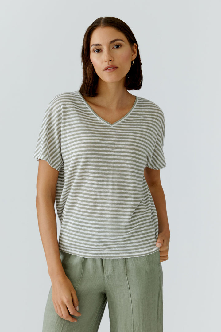 Femme portant un chandail à rayures col en v avec coupe décontractée et manches courtes, parfait pour un look moderne et quotidien.