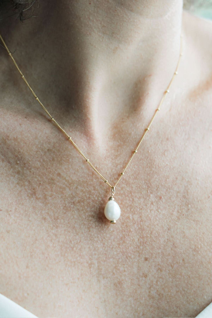 Chaîne en or vermeil avec une perle d'eau douce, élégante et minimaliste, portée par une femme.