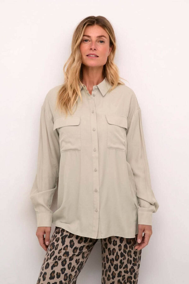 Chemise moderne beige à poches, manches amples et coupe fluide pour un look décontracté.