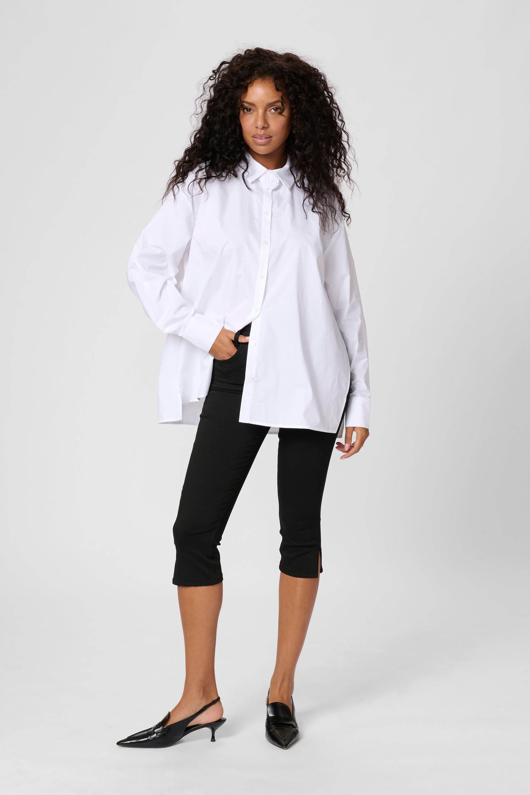 Chemise Mira ample en popeline de coton, brodée au col, portée avec un pantalon noir.